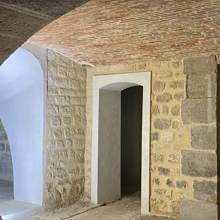 Intérieur d'un bâtiment avec des murs en pierre et une voûte en briques.